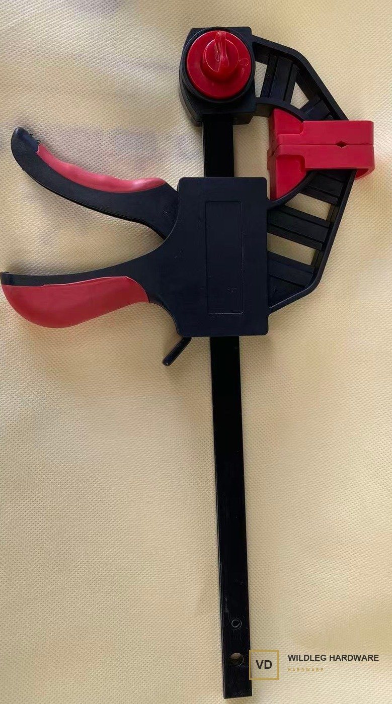A Wildleg trigger bar clamp: black nylon body, red grips, red jaw pads and a red jaw-release knob.