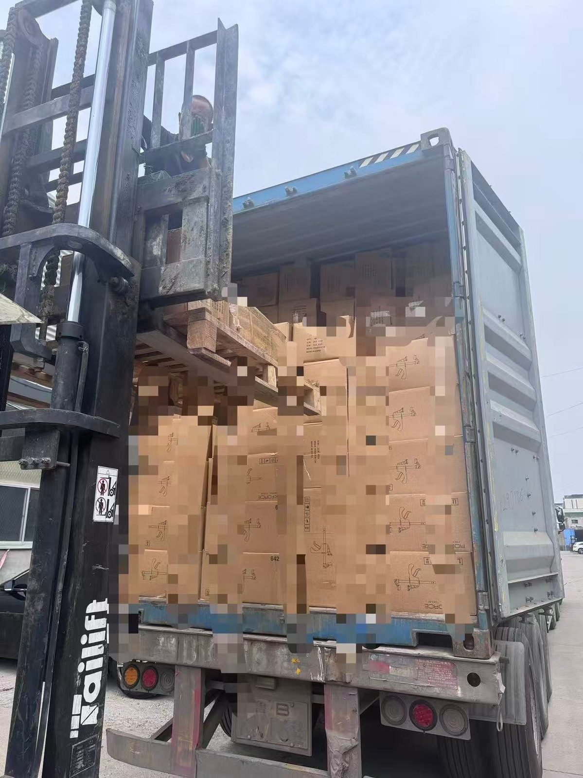 A forklift loading cartons of clamps into a shipping container for export.